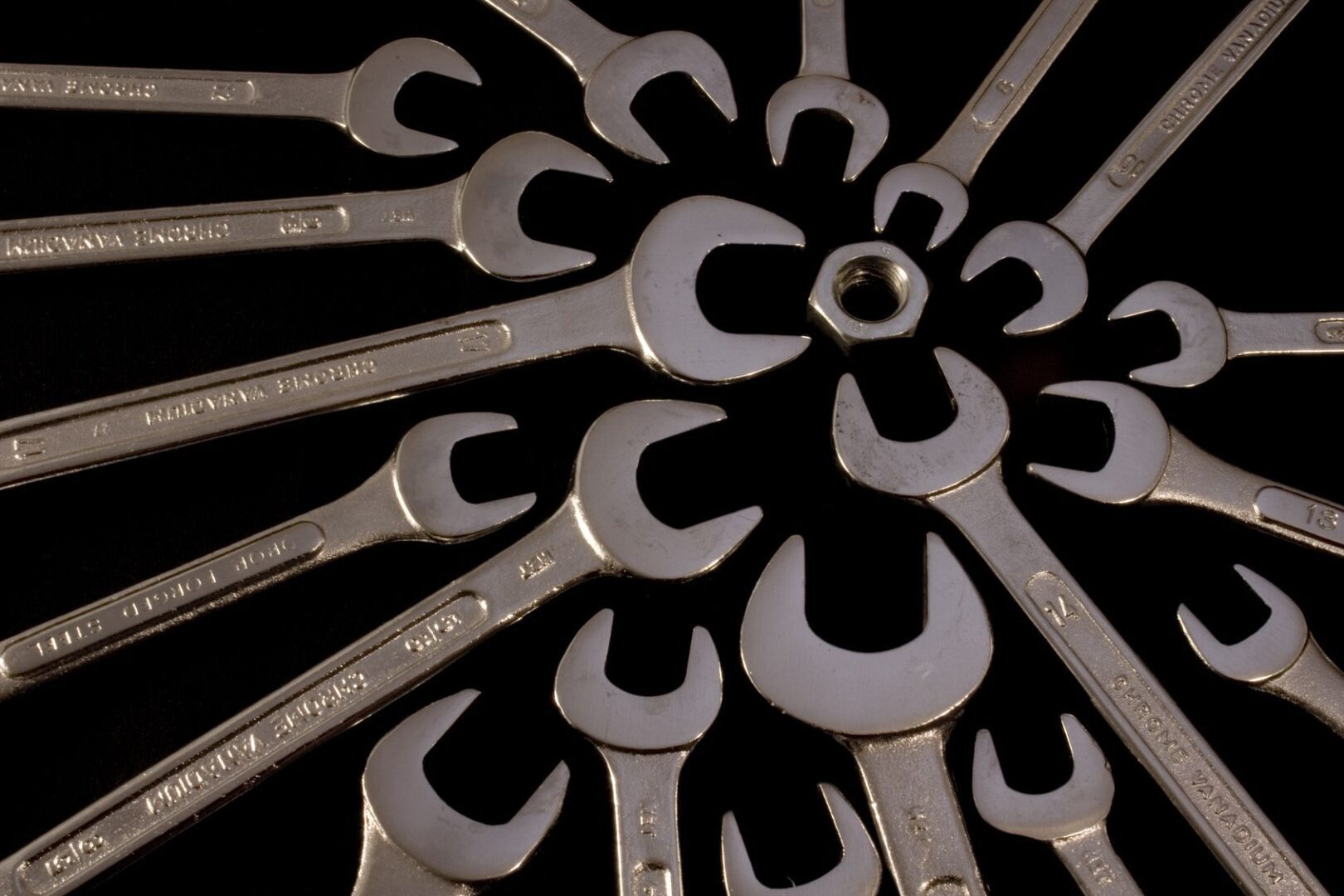 Wrenches arranged in a circular pattern with a nut in the center.